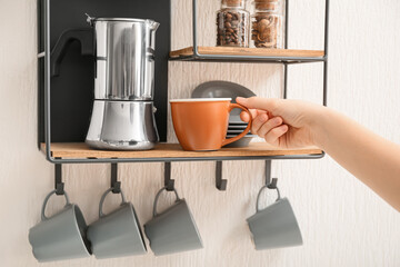 Woman putting cup on shelf in kitchen