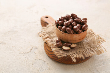 Fototapeta na wymiar Bowl with tasty chocolate nuts on white background