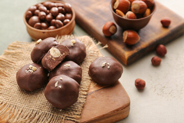 Tasty chocolate candies with nuts on light background, closeup