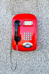 red payphone on a stone wall. pay phone on street. textured wall