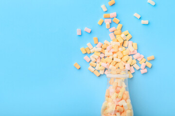 Bottle with sweet marshmallows on color background