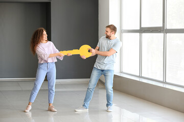 Happy young couple with big paper key in their new flat