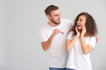 Happy young couple with key on grey background