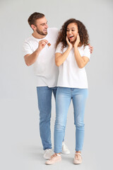 Happy young couple with key on grey background