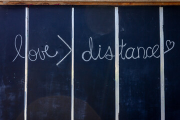 A blackboard with white text written in chalk that says love is greater than distance during...