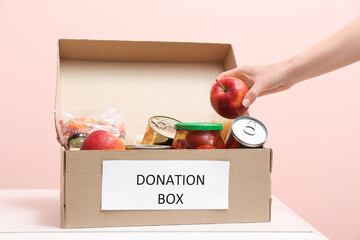 Woman putting products in donation box on table