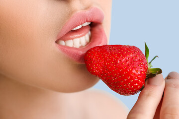 Sexy young woman with strawberry on color background, closeup