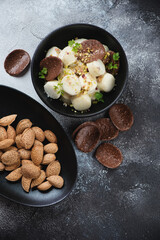 Bowl of vareniki or dumplings made of cottage cheese, above view on a dark-grey stone background, vertical shot