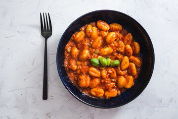 plant-based food, potato gnocchi with red pesto sauce and basil on top
