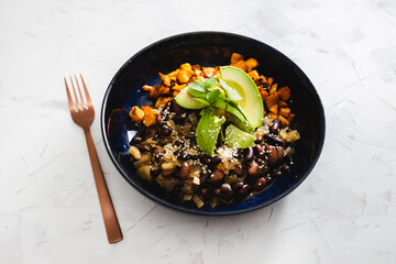 plant-based food, vegan mexican bowl with spicy beans pumpkin cubes and avocado topped with cfresh cilantro