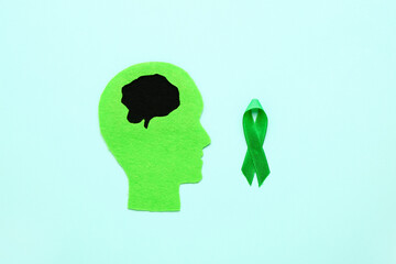 Human head with green awareness ribbon on color background. Concept of dementia