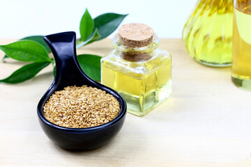Fototapeta na wymiar Flax seeds in a black ceramic bowl and flaxseed oil in bottles on wooden board