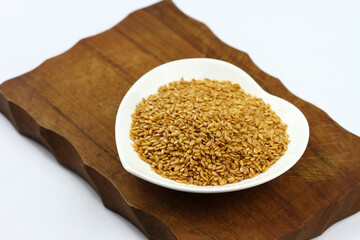 Flax seeds in a white ceramic bowl shape heart on wooden board