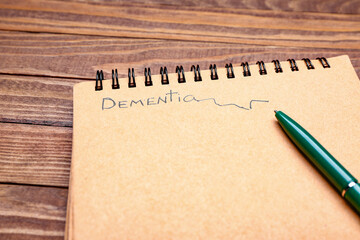 Notebook with word DEMENTIA and pen on wooden background