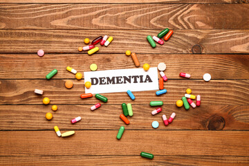 Word DEMENTIA with pills on wooden background