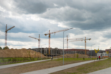 Construction cranes near the unfinished buildings. Construction and developing new districts