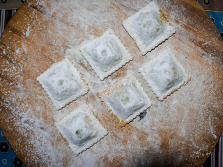 homemade ravioli on wooden board and flour