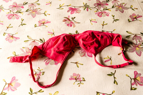 Red bra on morning bed sheet. Sunlight from window. Romantic passion female lingerie. Sexy fashion background. Still life.