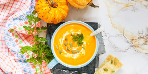 pumpkin cream soup on a table with ingredients, selective focus, top view, copy space