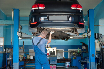Car service. Mechanic repairing chassis of the car