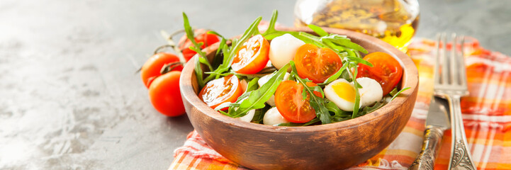 fresh arugula salad, cherry tomatoes, cheese and egg in a bowl on a table, selective focus, copy space