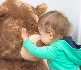 Cute child having fun playing with his giant teddy bear, at home