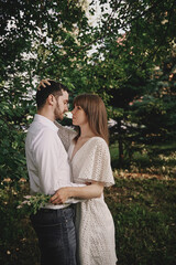 A guy and a girl kiss and walk in nature among the trees. Late evening romantic date at sunset.