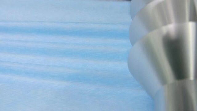 production conveyor makes goffers on blue material for masks
