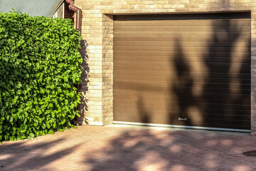 Brown garage doors of a private house and nearby lilac bushes.