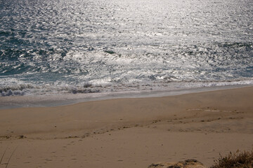 Empty beach at Vila do Conde Portugal in late afternoon with bright white reflections on water surface
