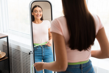 Excited Girl Measuring Thin Waist Looking In Mirror At Home