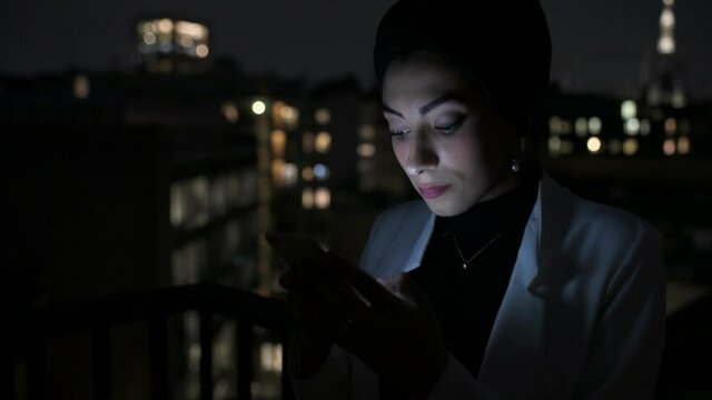 CU Young woman using smart phone on terrace at night / Milan, Italy