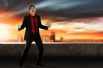 Fototapeta premium Asian businessman celebrating his successful standing on office terrace
