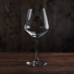 Empty wine glass on wooden table against dark background in bar. Catering Concept