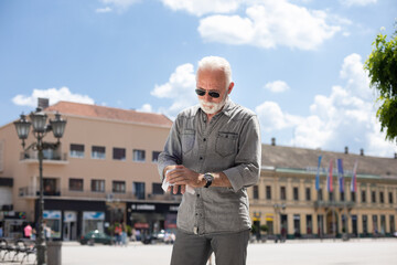 Old man cleaning hands with wet wipes outdoor