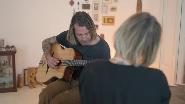 MS Woman assisting man playing acoustic guitar in living room / Milan, Italy