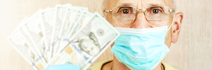 pensioner in blue mask holds dollar banknotes in fan closeup