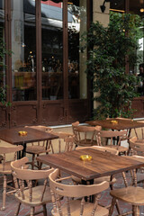 Athens Cafe exterior with wooden chairs and tables. Vertical travel photo. Quarantine closed cafe