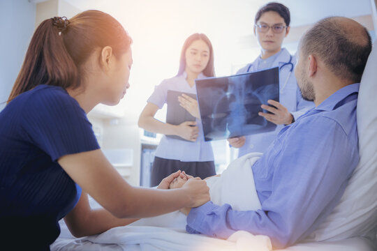 Doctor And Nurse Talk With Husband Patient About X-ray Result , Family Health Care , Palliative Care, With Wife Holding Hand Of Patient At Hospital