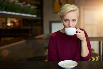 Caucasian young female enjoying cappuccino drink in coffee shop