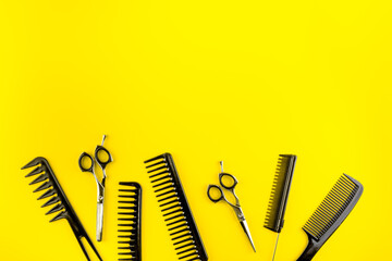 Combs, hairbrush, scissors - hairdresser eqiupment - on yellow table top-down space for text