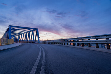 asphalt road and truss steel bridge during dusk