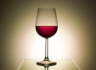 transparent glass with red wine on a reflective table