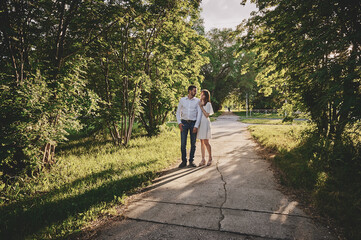 Obraz premium A guy and a girl are walking in the park. Romantic date evening walk. The relationship between people is love and tenderness.