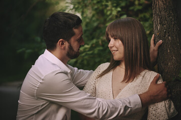 Fototapeta premium A guy and a girl are walking in the park. Romantic date evening walk. The relationship between people is love and tenderness.