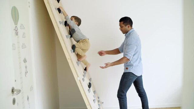 MS Father assisting son (2-3) on climbing wall in bedroom / Denmark