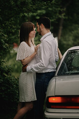 A guy and a girl are hugging next to a car. Romantic date evening walk. The relationship between people is love and tenderness.