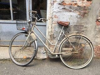 Old vintage bicycle leaning against the wall parked in a narrow street. 