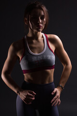 Obraz na płótnie Canvas Fitness young woman in training clothes, dark backlit photo