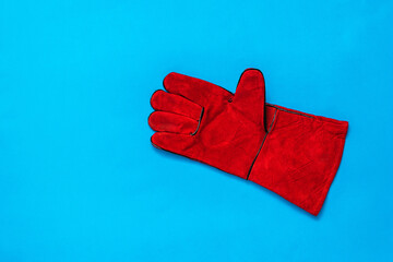 Red worker's glove on a bright blue background.